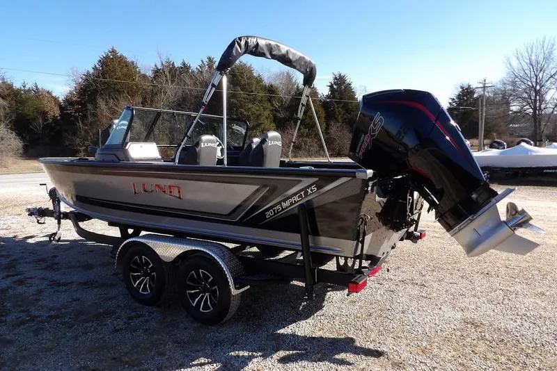 Slide: The Image of 2026 Lund 2075 Impact XS boat on trailer, parked outdoors, featuring sleek design and powerful engine. - 8