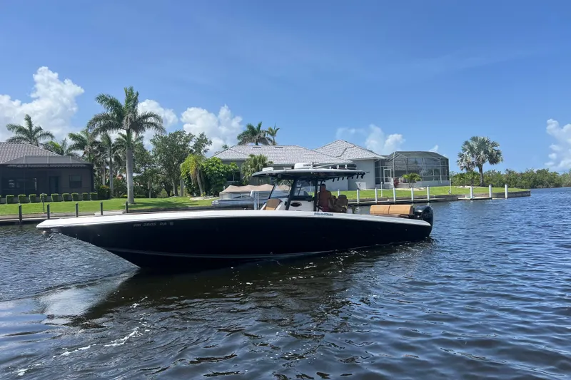 The Image of 2020 Fountain 38 Center Console boat on a sunny waterfront with palm trees. - 0