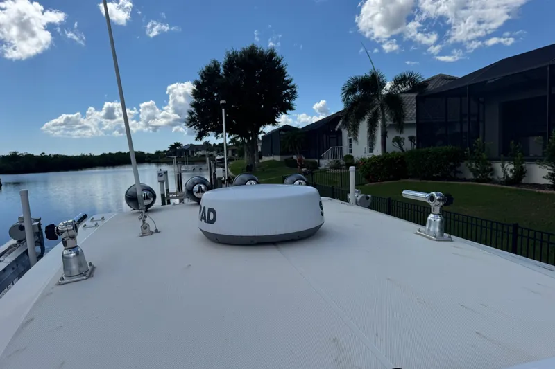 Slide: The Image of 2020 Fountain 38 Center Console boat docked by waterfront homes under a blue sky. - 20