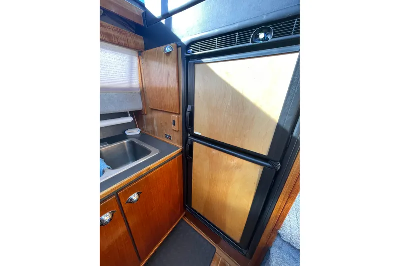 Slide: The Image of 1988 Bayliner 3888 Motoryacht kitchen with wood cabinetry and compact refrigerator. - 13