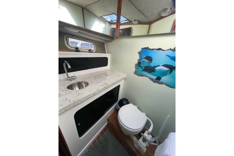 Slide: The Image of 1988 Bayliner 3888 Motoryacht bathroom with sink, toilet, and dolphin wall art. - 19