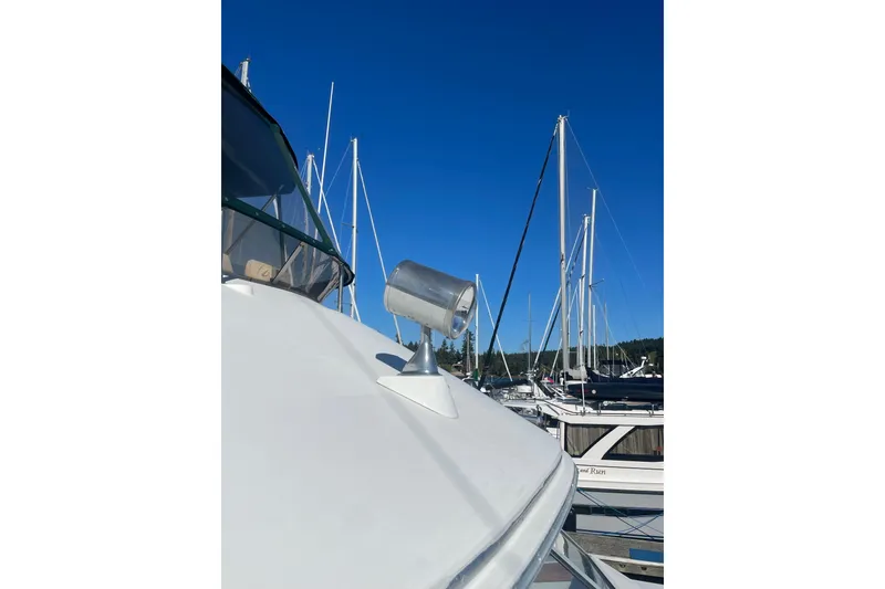 Slide: The Image of 1988 Bayliner 3888 Motoryacht docked, showcasing deck and spotlight against clear blue sky. - 27
