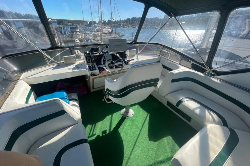 Slide: The Image of 1989 Bayliner 3888 Motoryacht cockpit with steering wheel, seating, and marina view. - 4