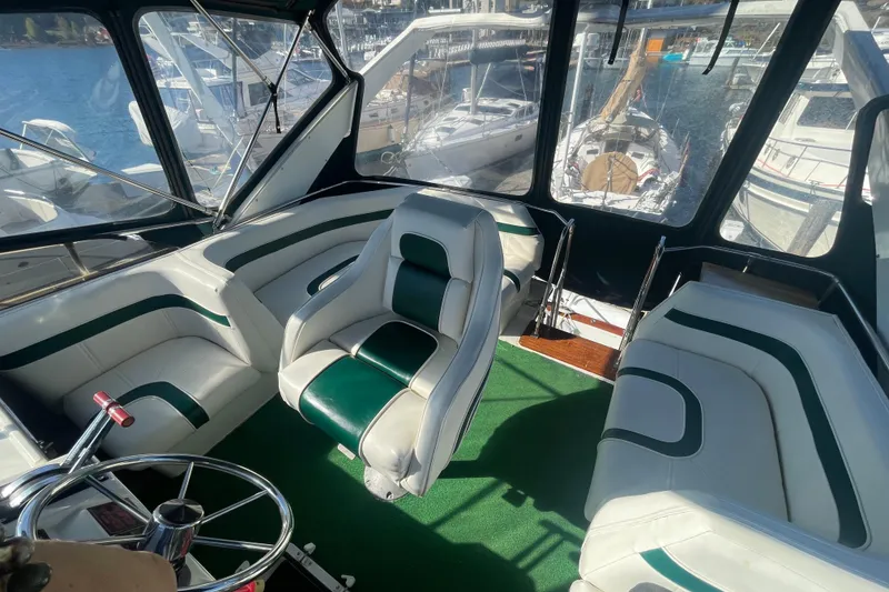 Slide: The Image of 1989 Bayliner 3888 Motoryacht interior with green and white seating, overlooking marina. - 6