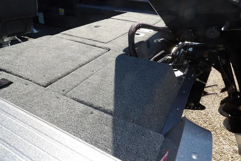 Slide: The Image of 2026 Lund 2075 Impact XS boat interior with carpeted deck and motor components. - 10