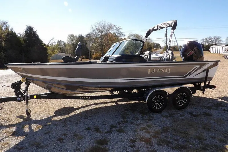 Slide: The Image of 2026 Lund 2075 Impact XS fishing boat on trailer, parked outdoors. - 2