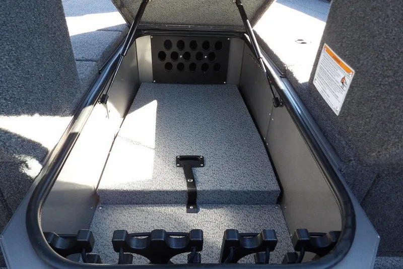 Slide: The Image of 2026 Lund 2075 Impact XS boat storage compartment with carpeted interior and rod holders. - 37