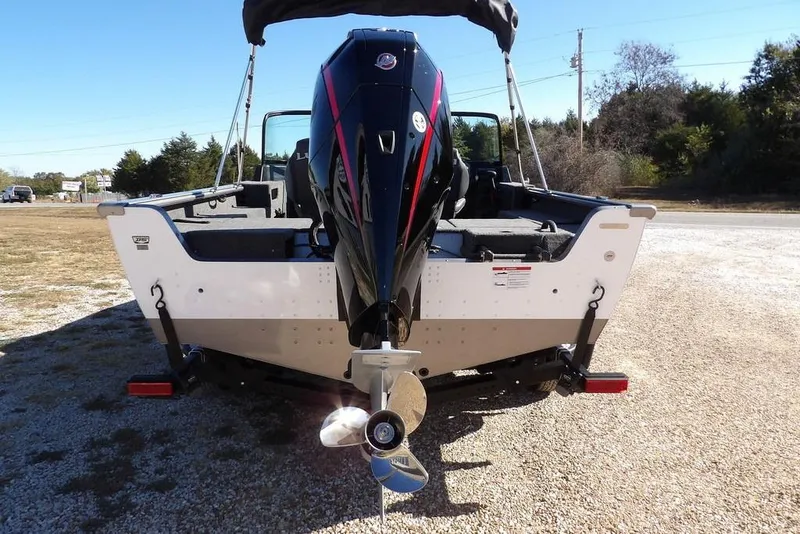 Slide: The Image of 2026 Lund 2075 Impact XS boat, rear view with outboard motor, parked on gravel. - 8
