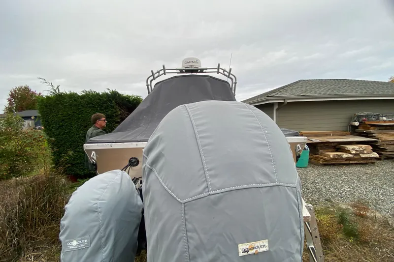 Slide: The Image of 2022 Duckworth 20XT Advantage boat covered, parked near a house with a person nearby. - 19