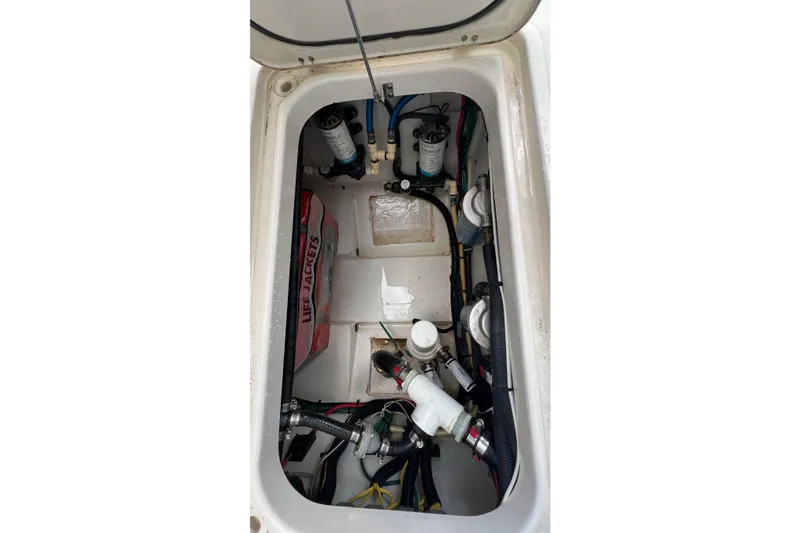Slide: The Image of 2015 Pursuit C 260 Center Console storage compartment with life jackets and mechanical components. - 21