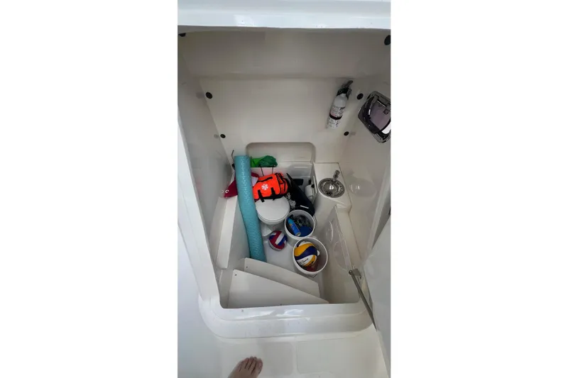 Slide: The Image of Storage compartment in 2015 Pursuit C 260 Center Console boat with various items. - 8