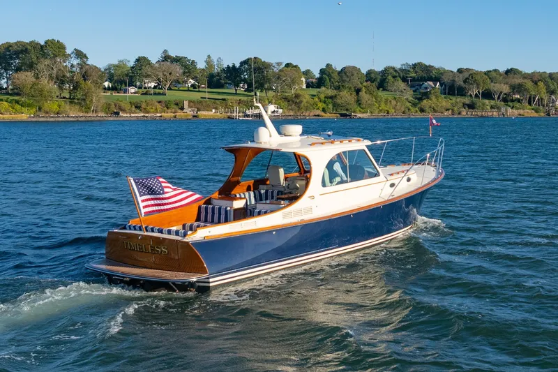 Slide: The Image of 2015 Hinckley Picnic Boat MK III cruising on a scenic lake with American flag. - 1