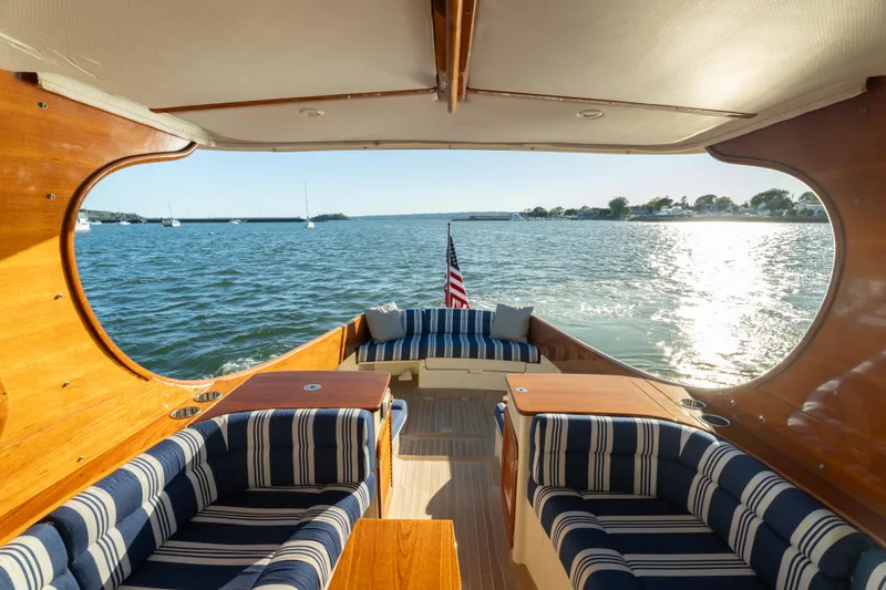 Slide: The Image of 2015 Hinckley Picnic Boat MK III interior with striped seating, overlooking serene waters. - 22
