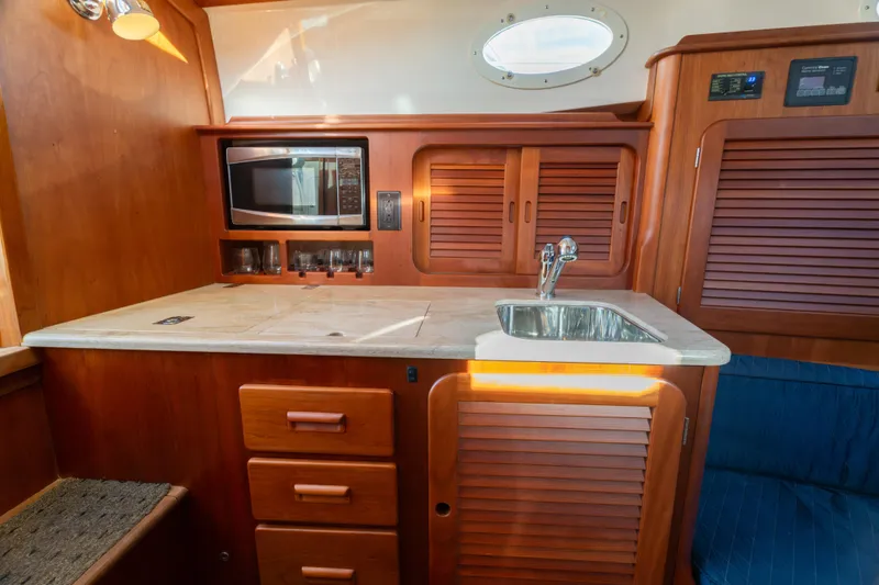 Slide: The Image of 2015 Hinckley Picnic Boat MK III interior with wooden cabinetry, sink, and microwave. - 25