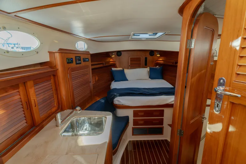Slide: The Image of Luxurious 2015 Hinckley Picnic Boat MK III cabin interior with wood finish and cozy bed. - 29