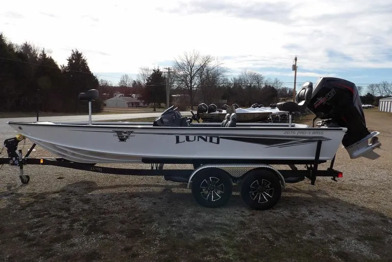The Image of 2026 Lund 2075 Pro-V Bass XS boat on trailer, parked outdoors. - 2