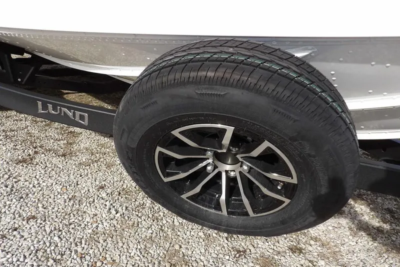 Slide: The Image of 2026 Lund 2075 Pro-V Bass XS trailer wheel on gravel surface. - 47