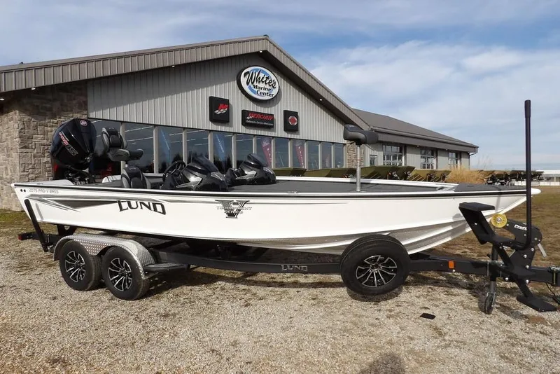 Slide: The Image of 2026 Lund 2075 Pro-V Bass XS boat on trailer outside marine center. - 5