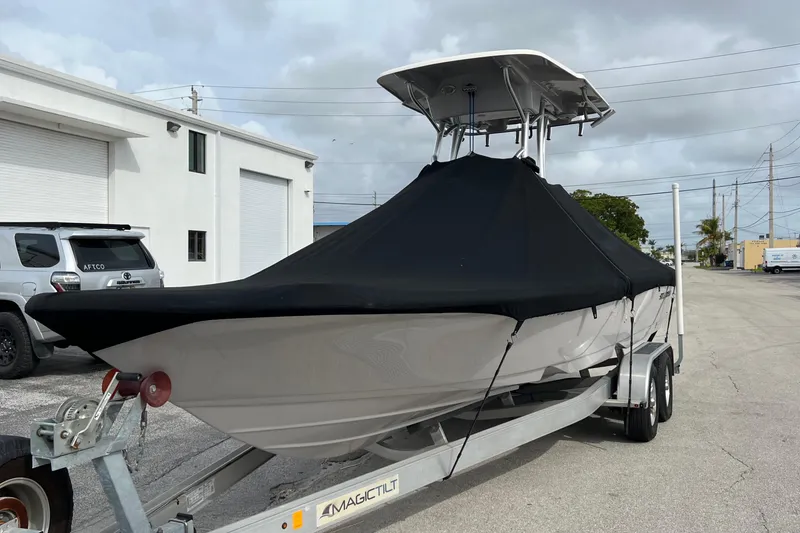 Slide: The Image of 2019 Sea Born FX24 Bay boat on trailer, covered, parked near industrial buildings. - 2