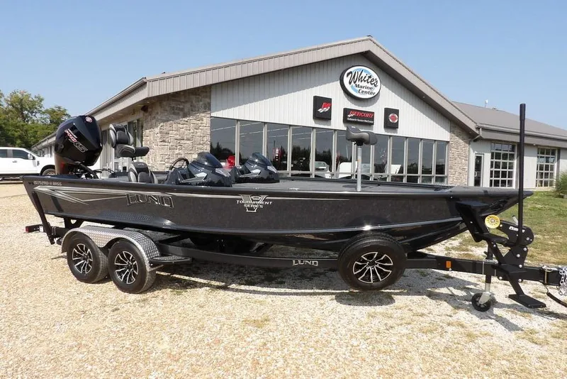 Slide: The Image of 2026 Lund 2075 Pro-V Bass XS boat on trailer outside marine center. - 2