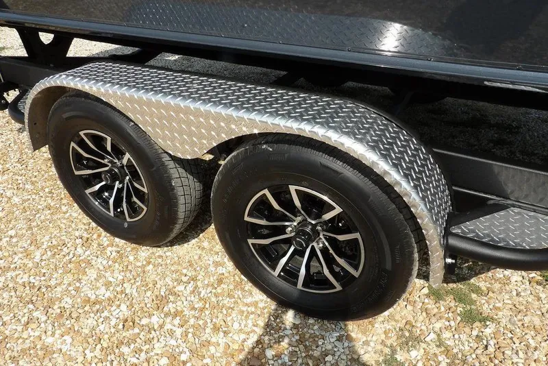 Slide: The Image of 2026 Lund 2075 Pro-V Bass XS trailer with dual black alloy wheels on gravel. - 51