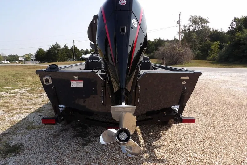 Slide: The Image of 2026 Lund 2075 Pro-V Bass XS boat with powerful outboard motor on gravel. - 6