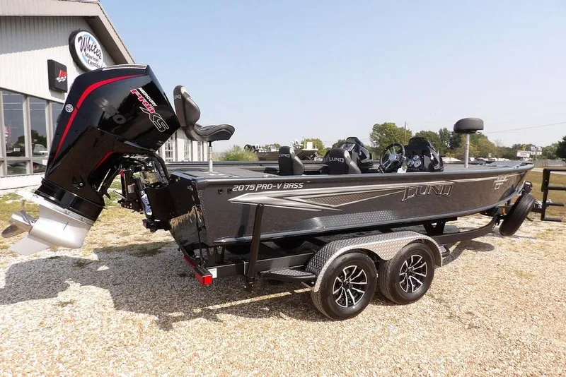 Slide: The Image of 2026 Lund 2075 Pro-V Bass XS boat on trailer, parked outdoors. - 7