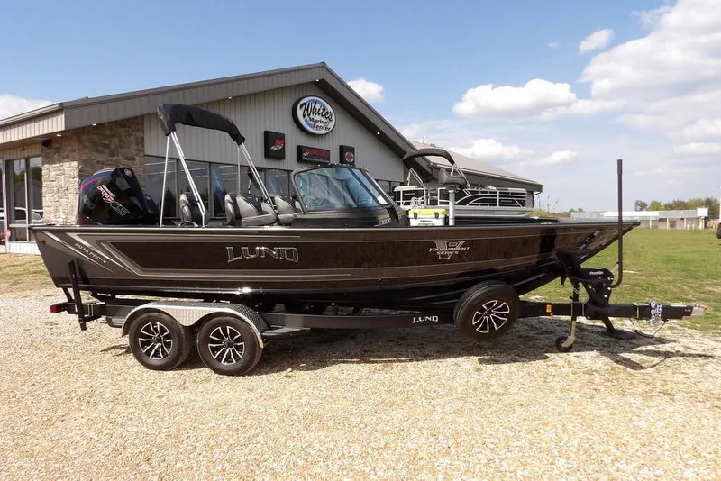 The Image of 2026 Lund 2075 Pro-V Sport boat on trailer, parked outside a marine center. - 1