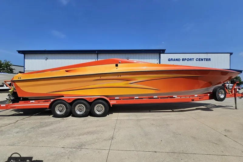 The Image of 1995 Hustler 40 Fiore speedboat on trailer, vibrant orange design, parked at Grand Sport Center. - 1