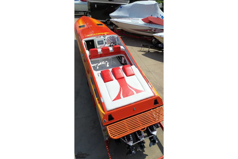 Slide: The Image of 1995 Hustler 40 Fiore speedboat with vibrant orange and white seating, docked outdoors. - 16
