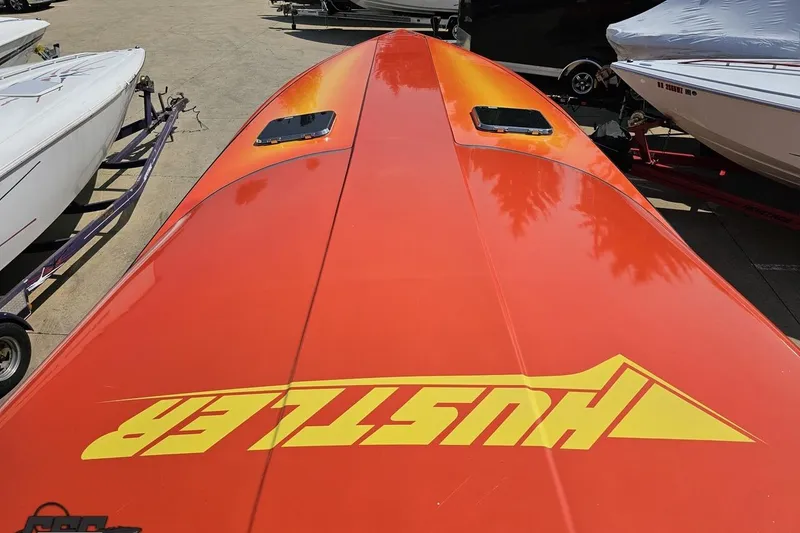 Slide: The Image of Orange 1995 Hustler 40 Fiore speedboat with bold yellow branding, parked among other boats. - 29