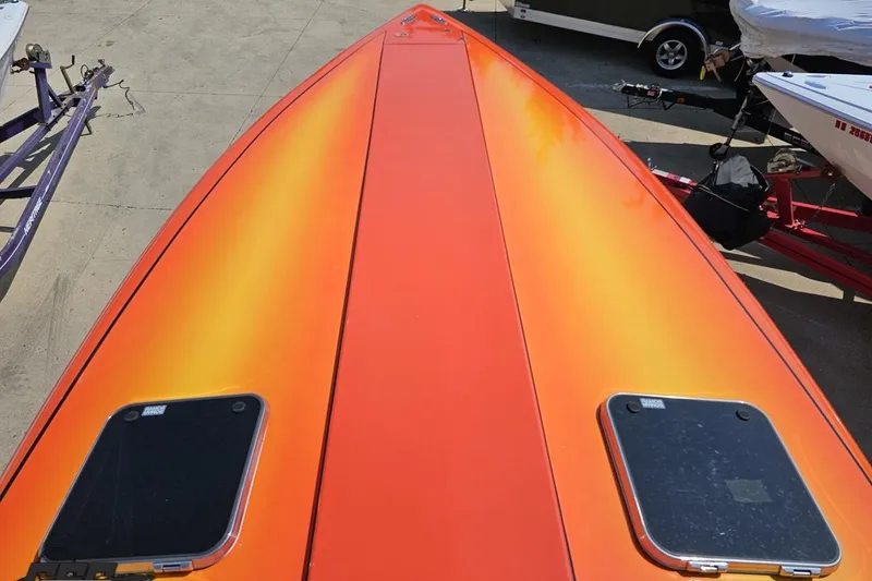Slide: The Image of Orange 1995 Hustler 40 Fiore boat deck, parked on concrete with trailers nearby. - 30
