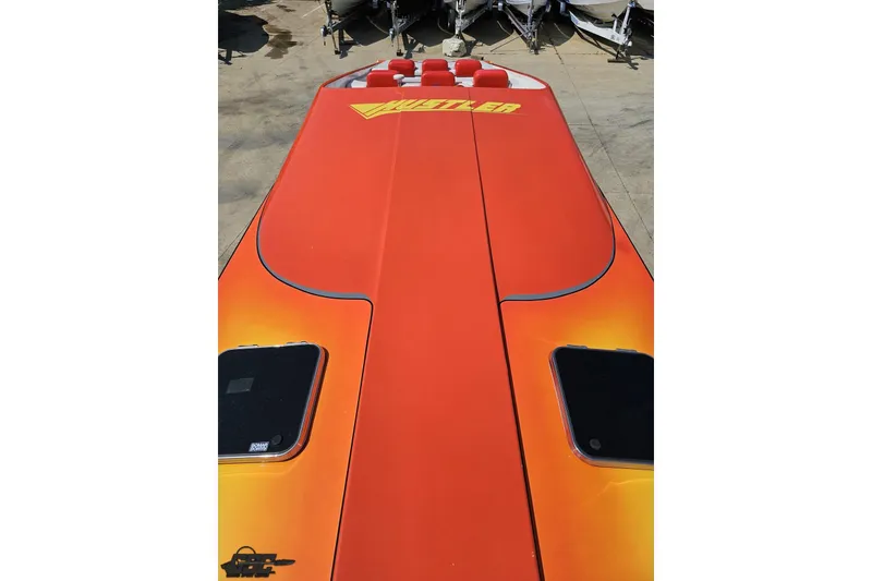 Slide: The Image of 1995 Hustler 40 Fiore boat with vibrant orange deck and logo, viewed from above. - 38