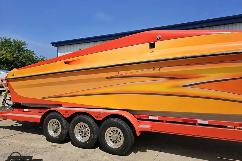 Slide: The Image of 1995 Hustler 40 Fiore speedboat on a trailer, featuring vibrant orange and yellow design. - 4