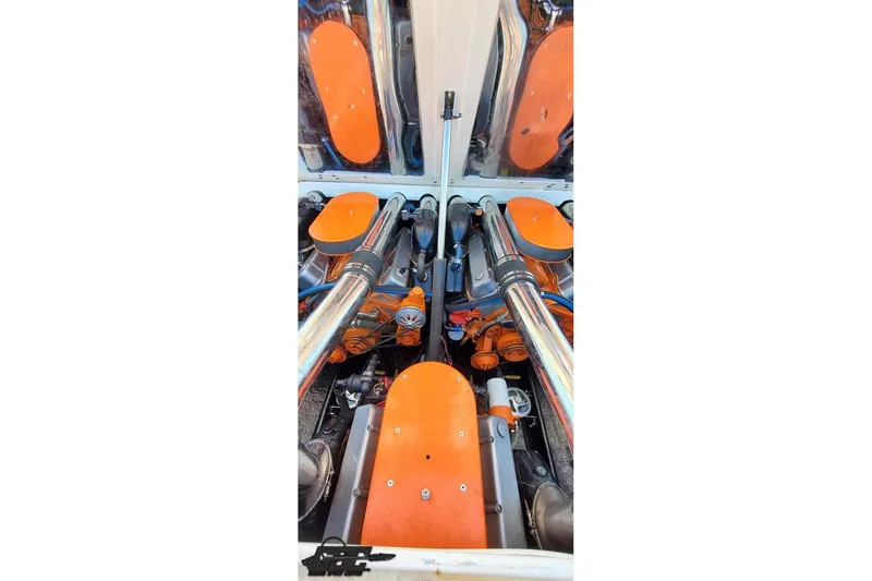 Slide: The Image of Engine compartment of a 1995 Hustler 40 Fiore boat with orange accents and chrome pipes. - 43