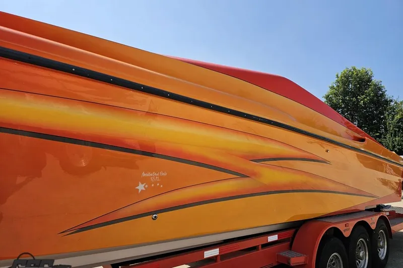Slide: The Image of 1995 Hustler 40 Fiore speedboat with vibrant orange and yellow design on a trailer. - 7
