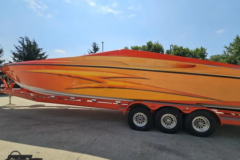 Slide: The Image of 1995 Hustler 40 Fiore speedboat on trailer, vibrant orange and yellow design, sunny day. - 9