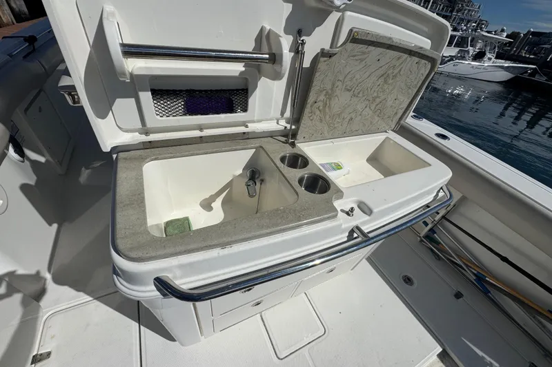 Slide: The Image of 2019 Boston Whaler 330 Outrage boat sink and storage area, docked by the water. - 11