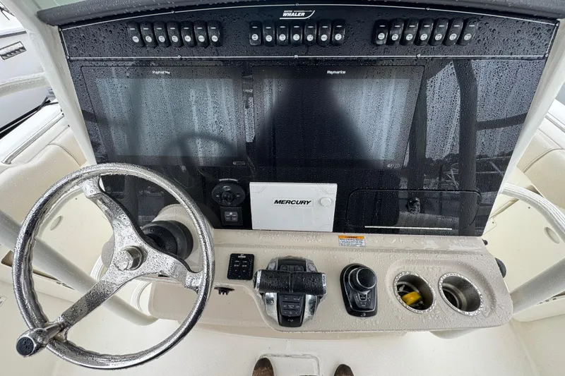 Slide: The Image of 2019 Boston Whaler 330 Outrage helm with steering wheel, controls, and electronic displays. - 13