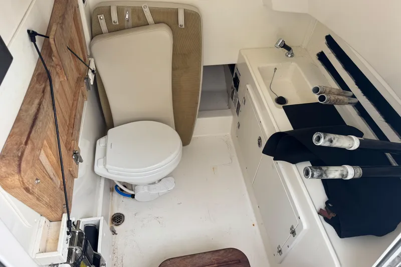 Slide: The Image of 2019 Boston Whaler 330 Outrage cabin with toilet, sink, and storage area. - 14