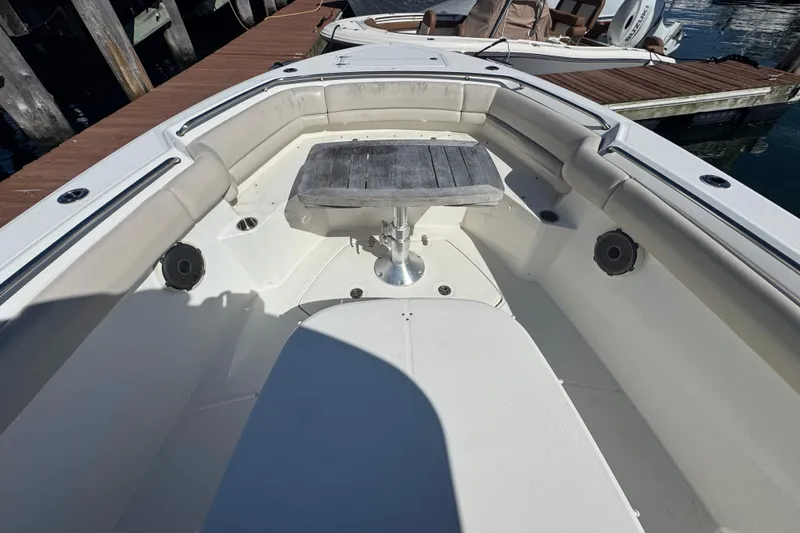 Slide: The Image of 2019 Boston Whaler 330 Outrage boat interior with seating and table, docked by wooden pier. - 5