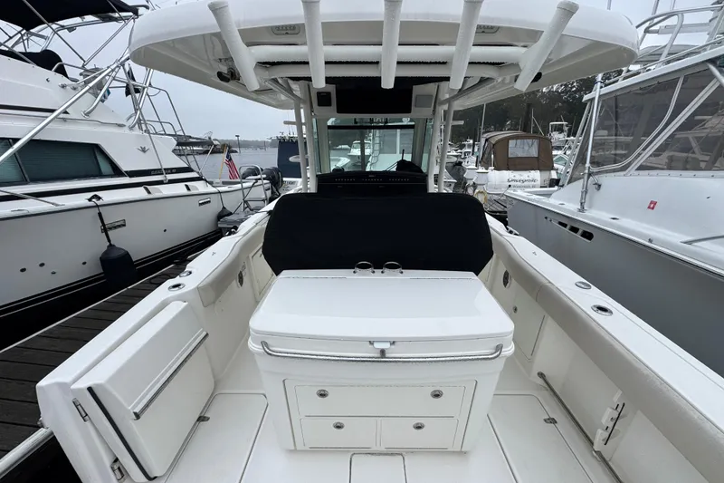 Slide: The Image of 2019 Boston Whaler 330 Outrage boat interior at marina, featuring seating and storage. - 8
