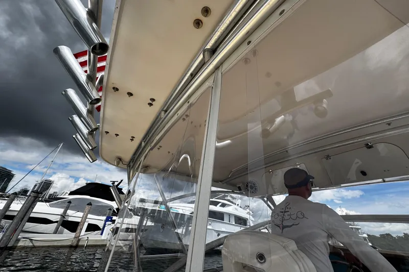 Slide: The Image of 2001 Grady-White Express 330 boat docked, with a person steering under cloudy skies. - 25