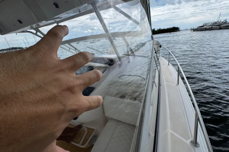 Slide: The Image of Hand reaching towards the helm of a 2001 Grady-White Express 330 boat on the water. - 52