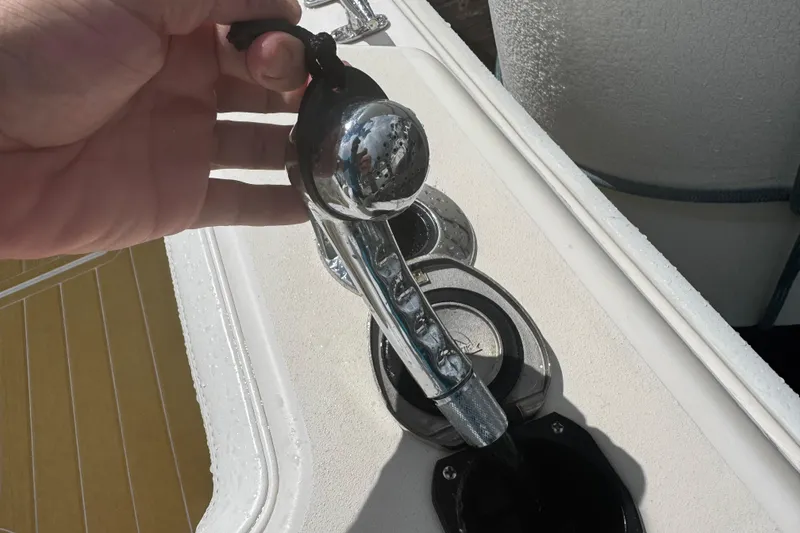 Slide: The Image of Hand holding a chrome lever on a 2001 Grady-White Express 330 boat deck. - 84