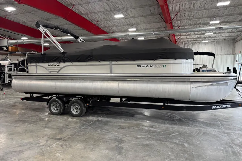 Slide: The Image of 2021 Lowe SS 270 pontoon boat with cover on trailer in indoor showroom. - 7
