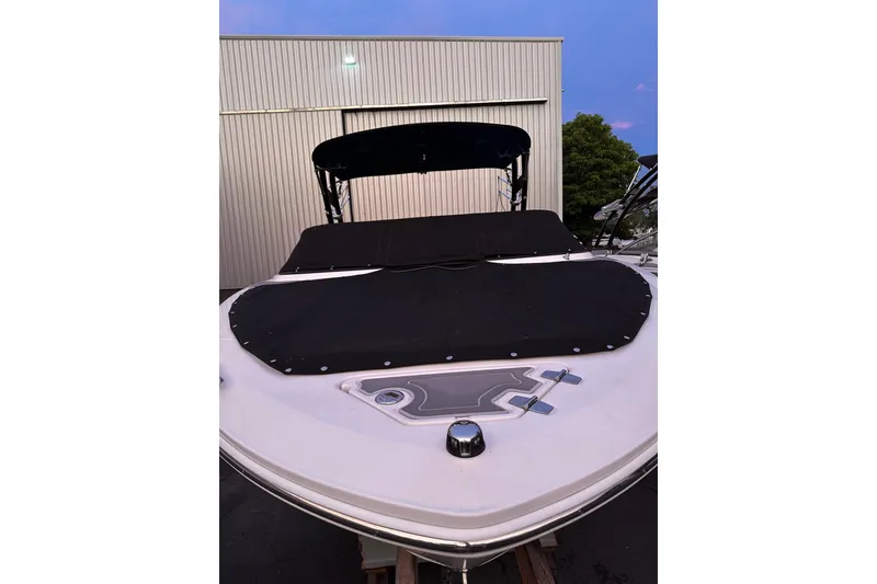 Slide: The Image of 2020 Regal LS2 Surf boat with black cover, docked near a building. - 38