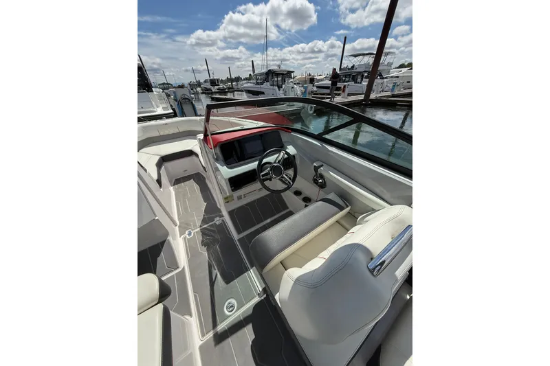 Slide: The Image of 2020 Regal LS2 Surf boat interior with steering wheel, docked at marina under cloudy sky. - 12
