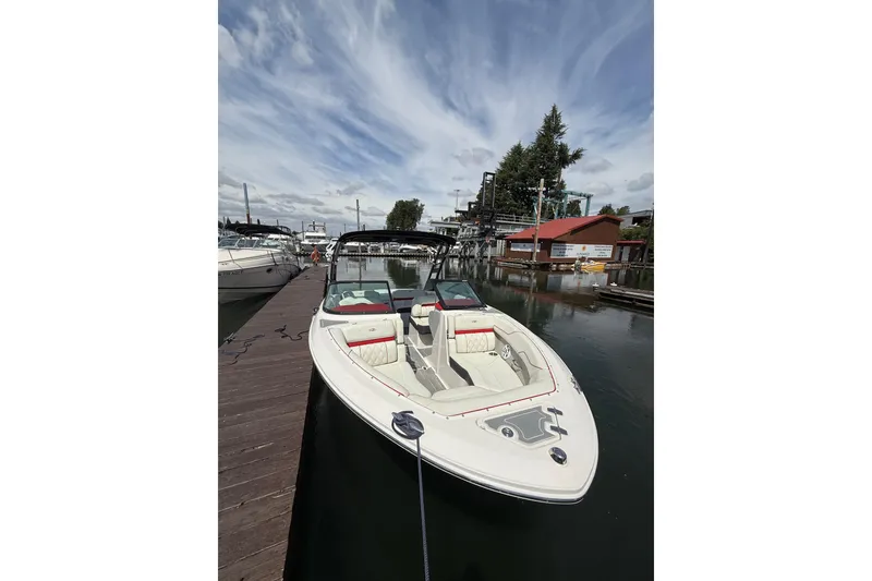 Slide: The Image of 2020 Regal LS2 Surf boat docked at marina under a partly cloudy sky. - 2