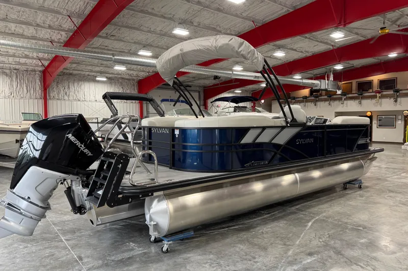 Slide: The Image of 2025 Sylvan X-5 pontoon boat in a showroom with red beams and Mercury outboard motor. - 3